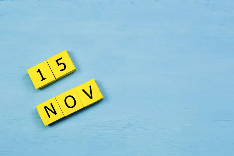 nov 15, yellow cube calendar on blue wooden surface with copy space