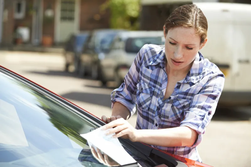 frustrated female motorist looking at parking ticket