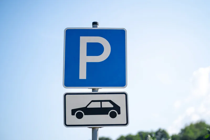 blue and white parking lot sign with p letter and pictured car in the parking lot taken in daytime in summer