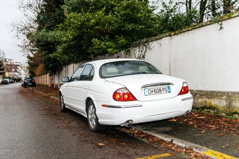 strasbourg, france - jan 1, 2019  rear view of white luxury jaguar limousine parked on a street under fir tree