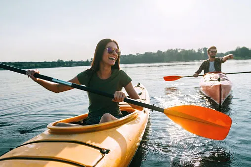 beautiful young couple kayaking on lake together and smiling