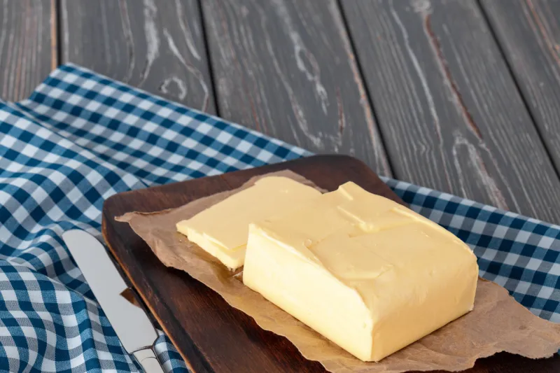 wooden board with butter on blue checkered napkin, close up
