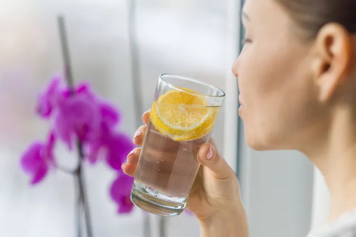 woman drinking summer refreshing fruit flavored infused water with fresh organic lemon healthy eating, diet concept