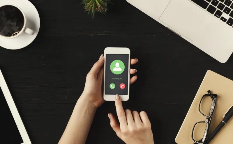 incoming call, communication concept top view female hands holding smart phone, flat lay, dark table in background