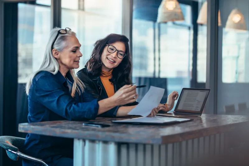 two women analyzing documents while sitting on a table in office woman executives at work in office discussing some paperwork