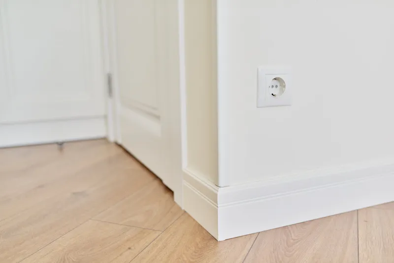 repair in the house, apartment, close-up detail of the interior, white floor plinth, finishing the corner of the wall with a wooden painted plank