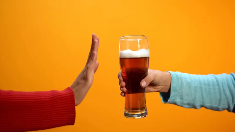 female rejecting beer glass showing stop gesture, bad habit refusal, health care