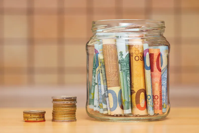 euro banknotes in a glass jar, columns of coins close-up the kitchen background is blurred the concept of finance and economics