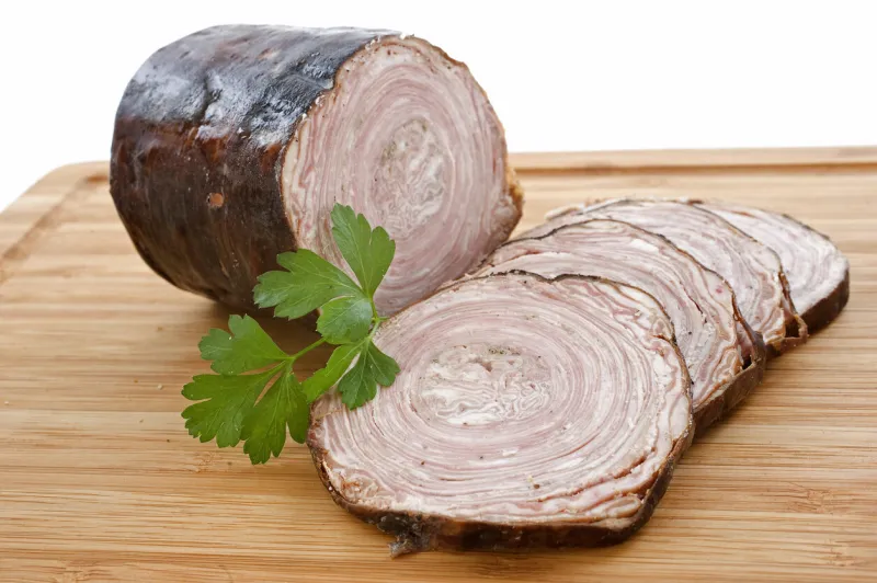 andouille de guemene, french sausage on a cutting board with parsley