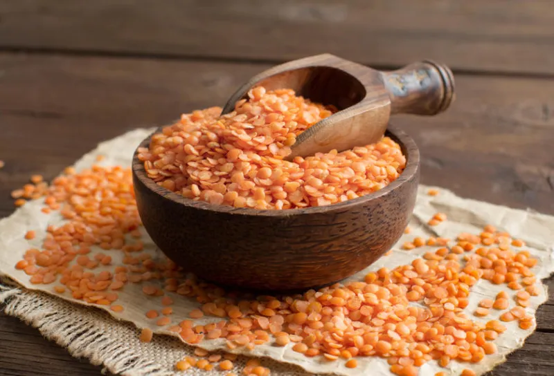 lentilles rouges dans un bol avec une cuillère sur une table en bois