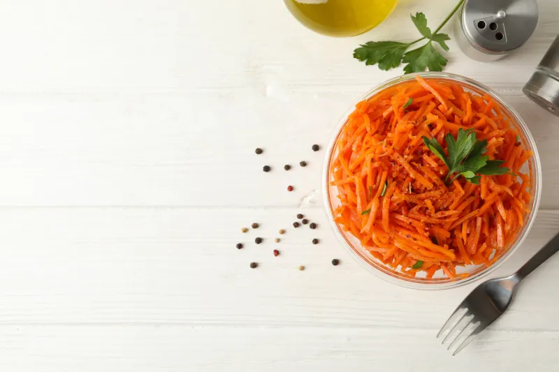 composition with tasty carrot salad on white wooden background korean carrot