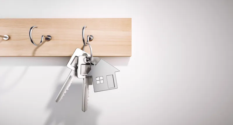 house keys with key ring hanging on wooden board