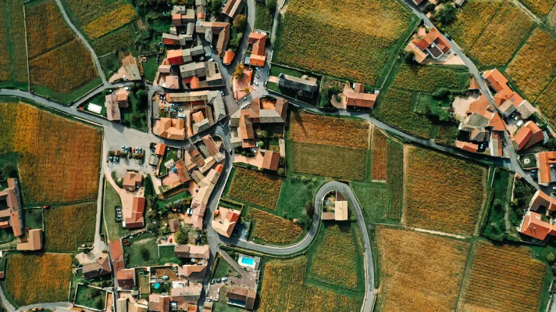 aerial shot of a french village with orange roofs, winding roads and surrounded by vineyards - stock photo