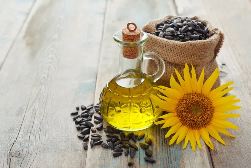 sunflower oil in bottles with seeds and flower on wooden background