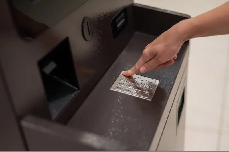 faceless woman dialing bank card pin at atm