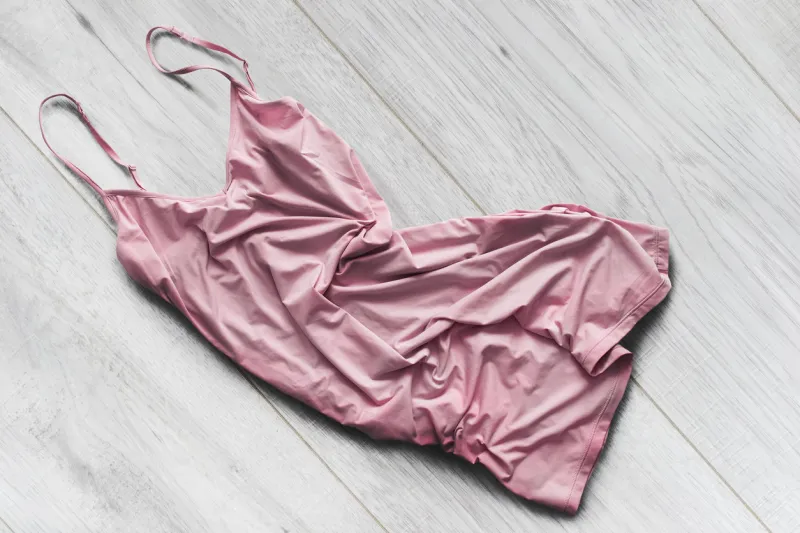 crumpled pink silk dress on white wooden background