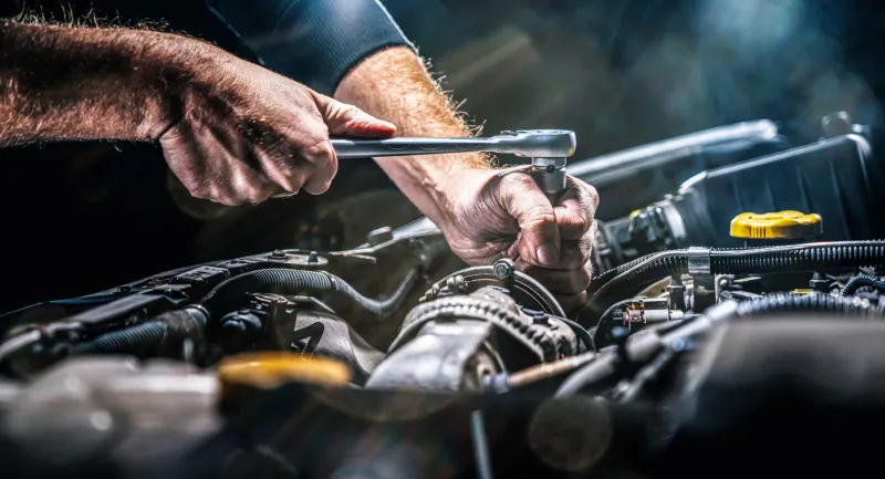 auto mechanic working on car engine in mechanics garage repair service authentic close-up shot
