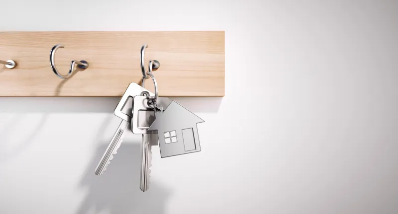 house keys with key ring hanging on wooden board