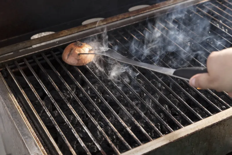 getting the grill ready for some cooking - rubbing halved onion on the hot grate