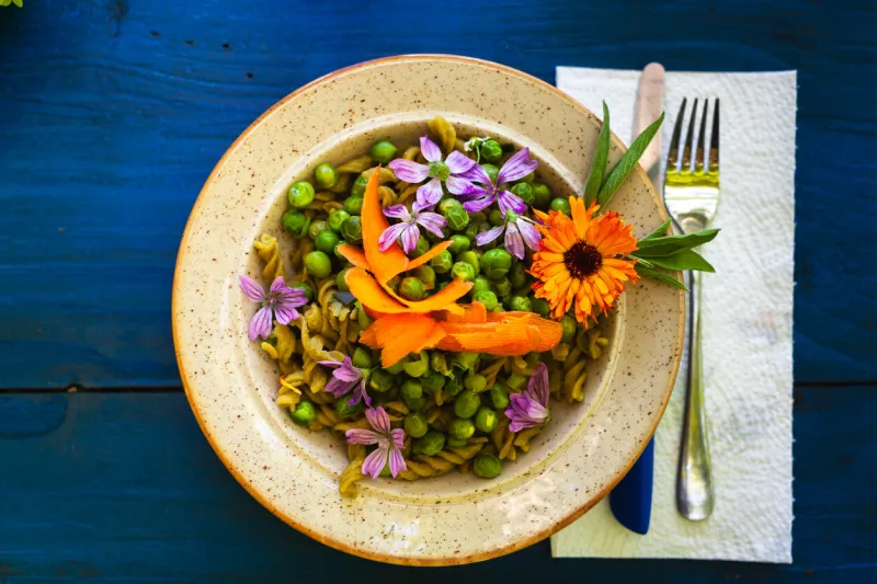 flowers of calendula and malva in a dish of green peas - floral dish concept and healthy eating