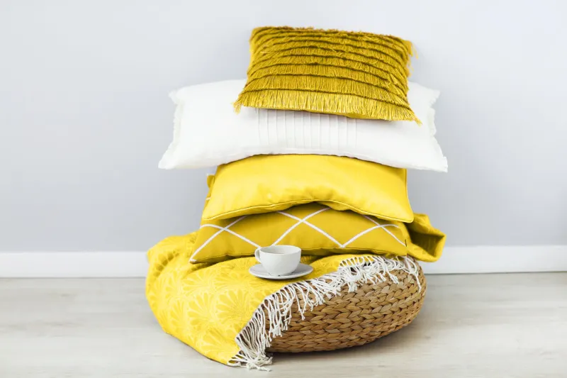 pink and white pillows and cup of coffee on the wall background close up