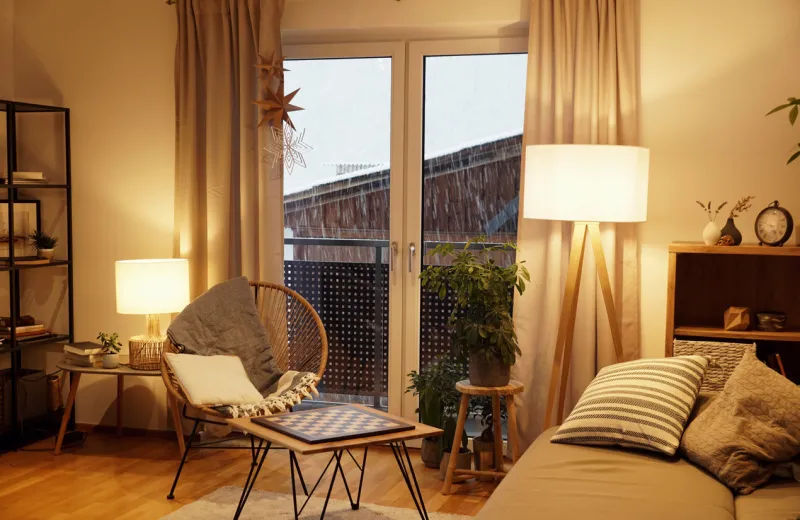 cozy scandinavian style living room with a rack, a comfortable seat and a table lamp in winter