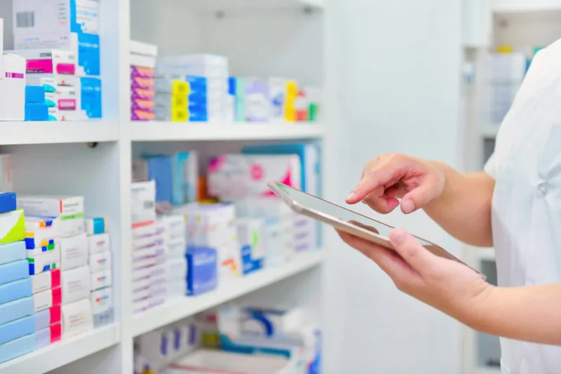 pharmacist holding computer tablet using for filling prescription in pharmacy drugstore