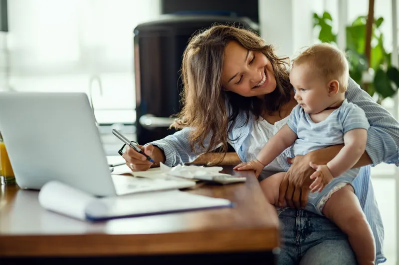 young happy mother going through home finances and communicating with her baby son