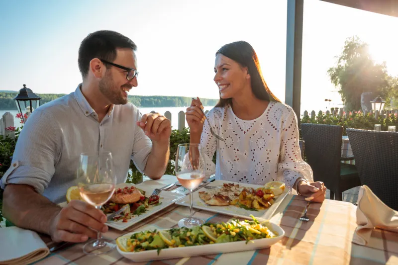 beautiful happy young couple making a toast, celebrating anniversary or birthday in a restaurant husband and wife having romantic dinner in a restaurant by the river