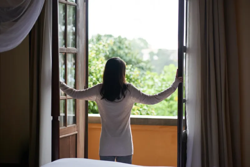 rear view of young woman enjoying view from balcony of her room