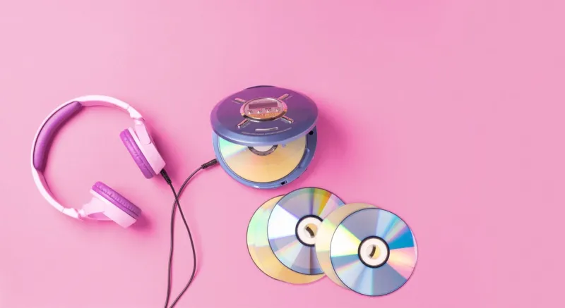 personal compact portable cd player disks purple headphones on a pink background top view layout, copy space, place for text or advertising hobby entertainment leisure