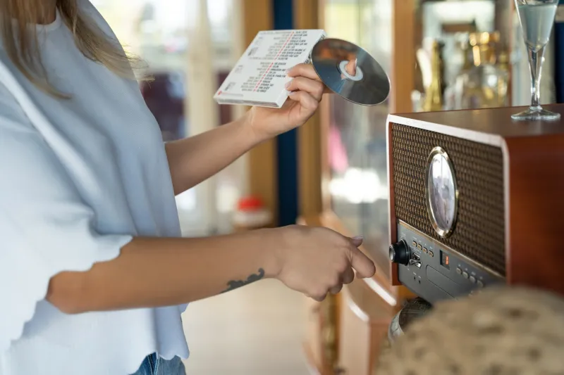 close-up woman changes music cds in vintage cd-player at home relaxation, leisure, hobby, music in daily life