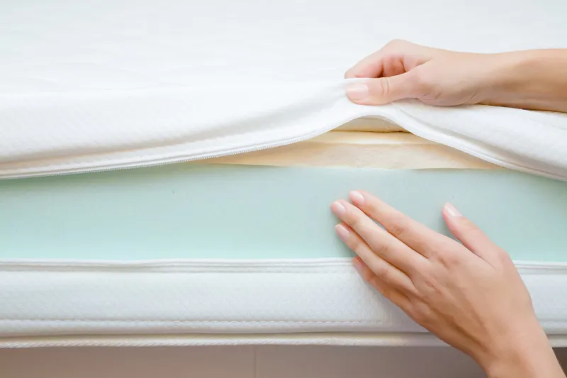 woman's hands touching different layers of new mattress checking hardness and softness choice of the best type and quality front view close up