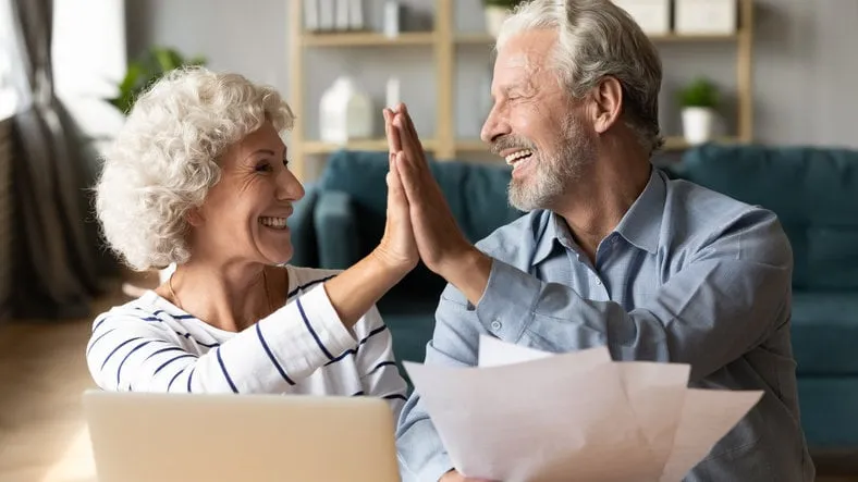 excited older couple giving high five, mature family celebrating success, checking or paying domestic bills, planning budget, smiling mature man holding financial documents, reading good news