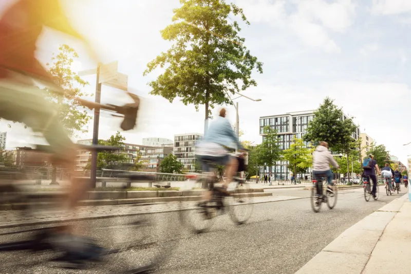 motion blurred cyclists riding inside a city on a sunny day