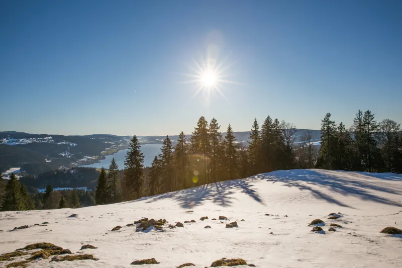 scenic view of mountain lake and forest on a sunny winter day