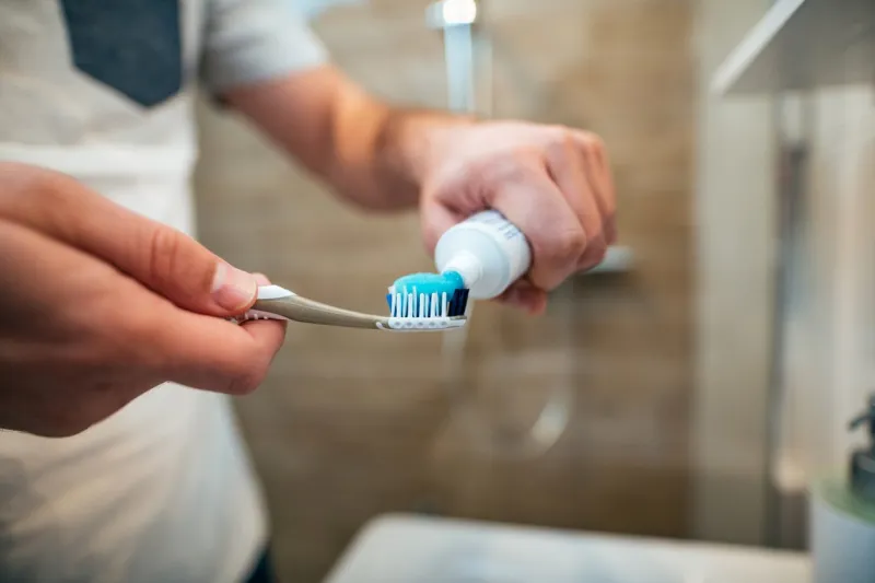 dental health care concept close-up of man squeezes toothpaste on the toothbrush