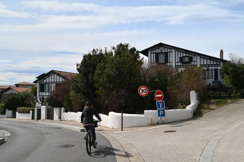 bidart, france, march 9, 2022   cyclist on a street in bidart with basque houses in the background
