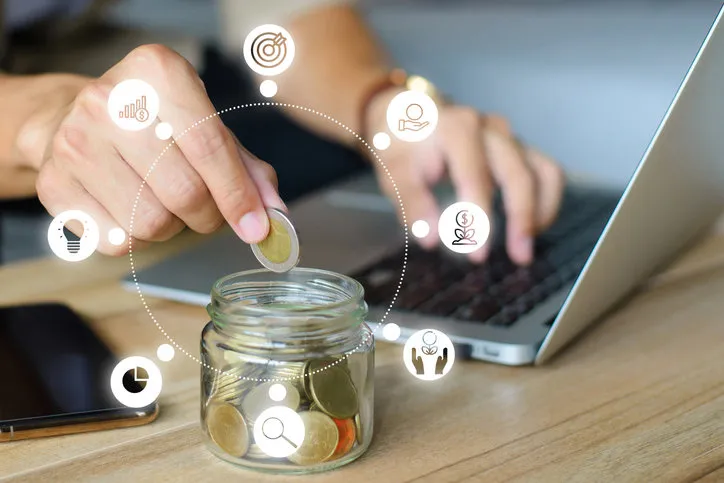 young man hand putting money coin stack in the jar for the future, growing business, education and retirement this concept is about saving money and investing money to grow