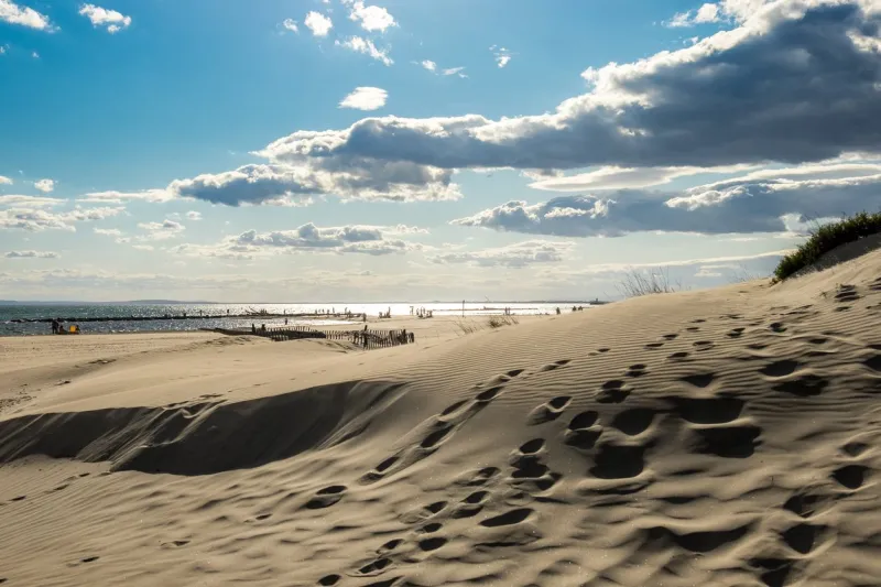 landscape view of small sand dunes with the sea and cloudy sky in the background, shot in agde, france