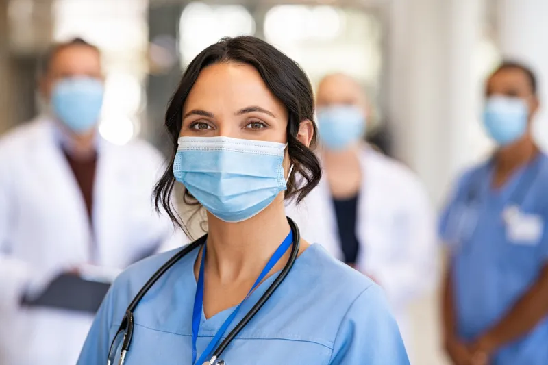 happy nurse with face mask smiling at hospital
