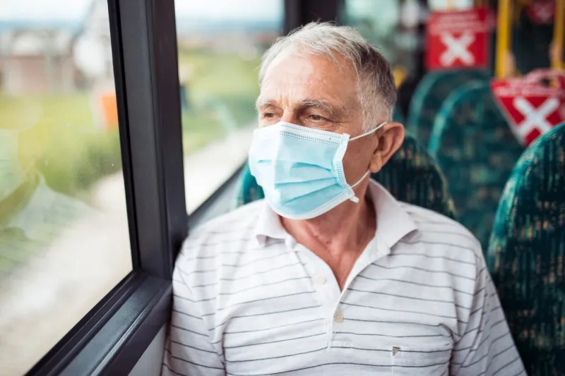 senior man with respiratory mask traveling in the public transport by bus