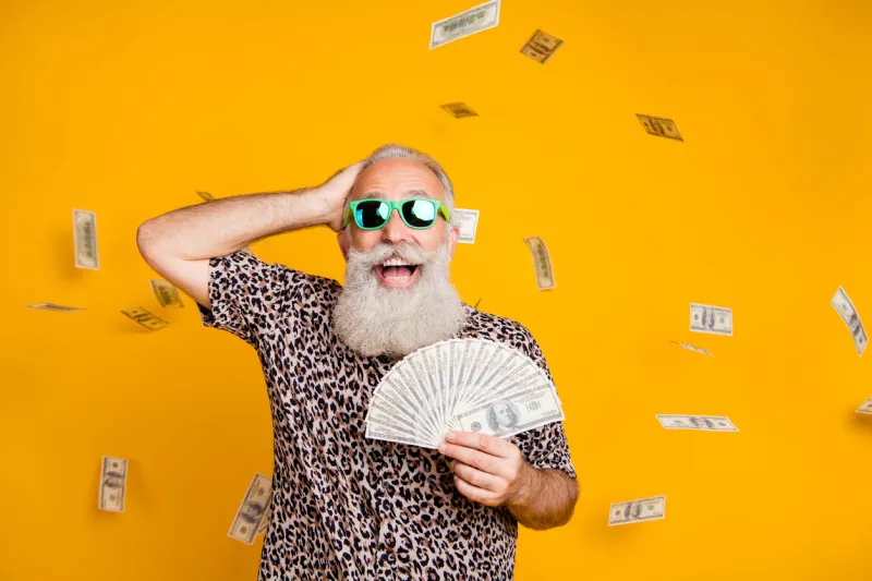 portrait of retired old funny bearded man in eyewear eyeglasses scream omg, look at falling money win lottery wearing leopard t-shirt isolated over yellow background