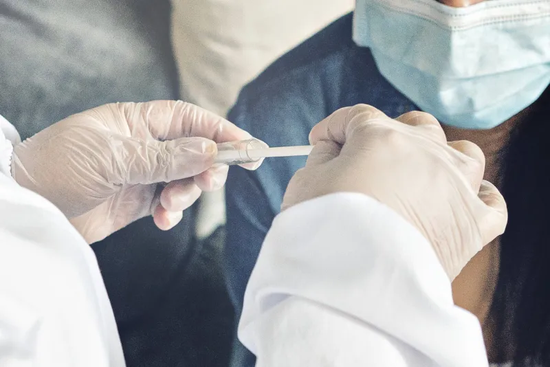 a doctor in a protective suit performs a coronavirus test for the covid-19 viruspandemic concepts