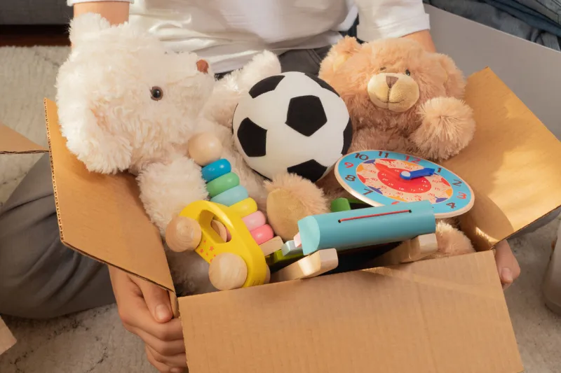 teenager sorting and collect kid toys, clothes into boxes at home donations for charity, help low income families, declutter home, sell online, moving into new home, recycling, sustainable living