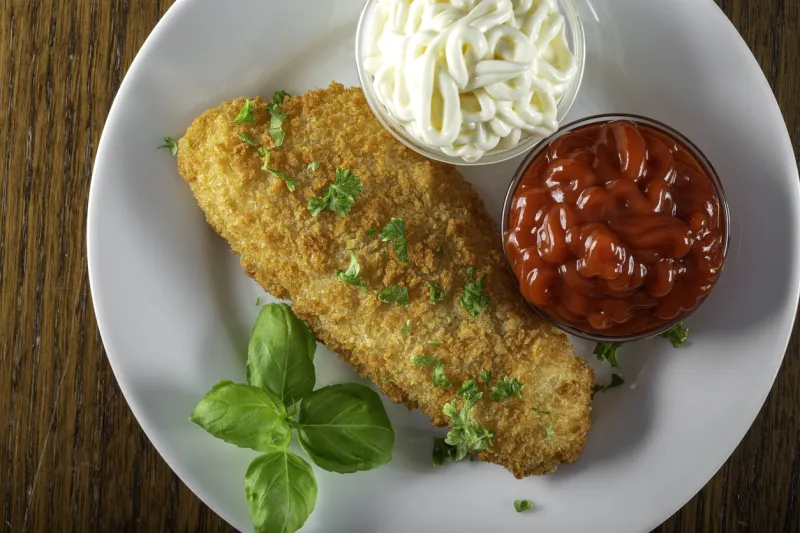 fried fish with ketchup and mayonnaise sauce - top view