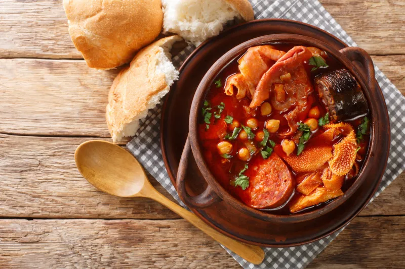 hot callos madrilenos made from tripe, chorizo, blood sausage and chickpeas in a spicy sauce close-up in a bowl on the table horizontal top view above