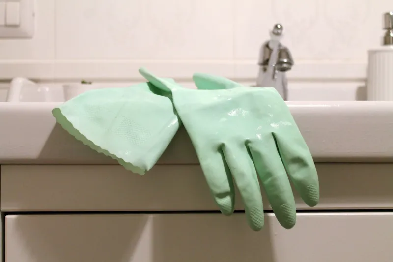 close-up of a pair of green rubber gloves for cleaning a sink