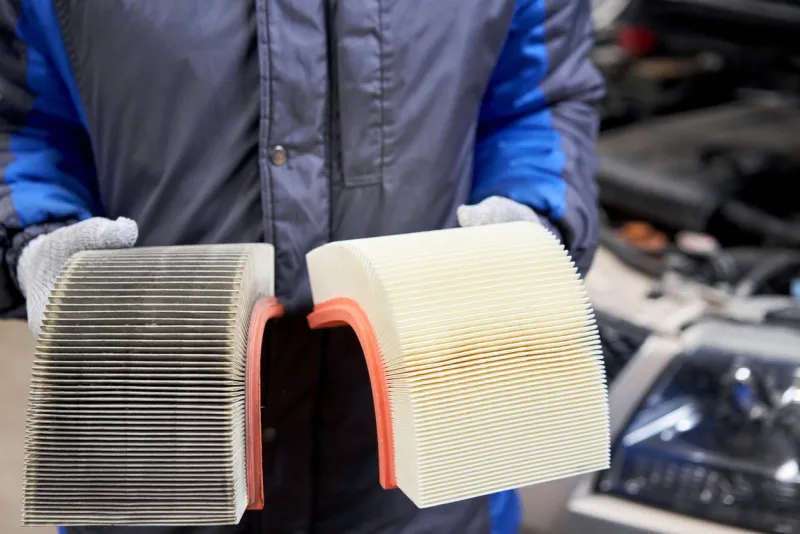 new and old dirty automotive engine air filter in the hands of an auto mechanic auto repair concept