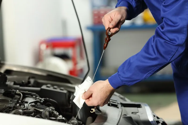 close up of a car mechanic checking oil level in a mechanical workshop